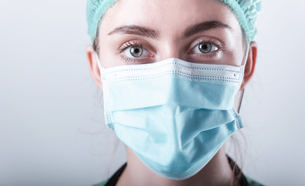 Female Doctor in Protective Mask and Medical Cap on Isolated Background, Closeup Portrait of Medicine Surgeon Doctor Wearing Medical Mask With Copy Space. Clinical Health Care/Doctors Occupation